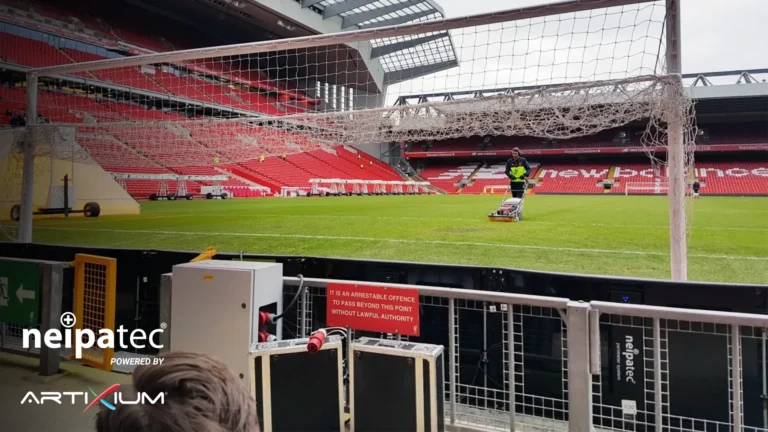 Écran LED stade Anfield – Système LED périmétrique NEIPATEC vu de l’arrière au bord de la pelouse d’Anfield, gradins vides