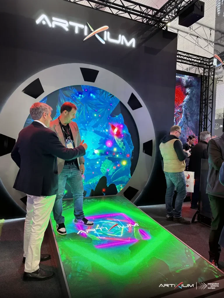 Deux visiteurs debout sur un sol LED devant un écran circulaire aux motifs végétaux lumineux