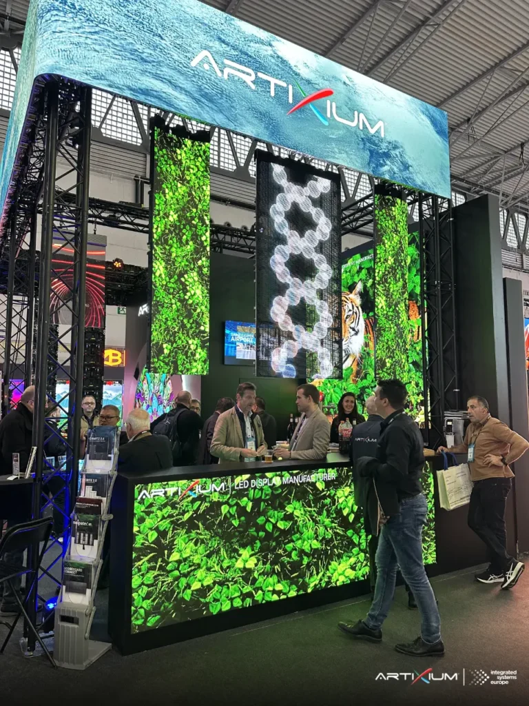Comptoir et colonnes LED du stand diffusant des visuels de feuillage devant des visiteurs