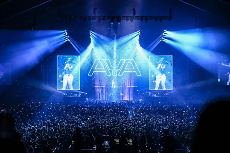 Écran LED tournée Aya Nakamura – Écrans LED latéraux et logo AYA au centre de la scène, arène comble sous les faisceaux bleus