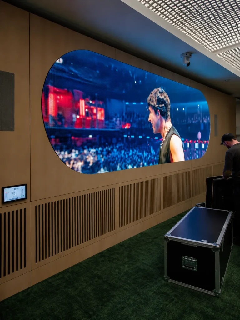 LED screen headquarters – Oval LED display set into the timber wall showing a concert, technician and flight case in front