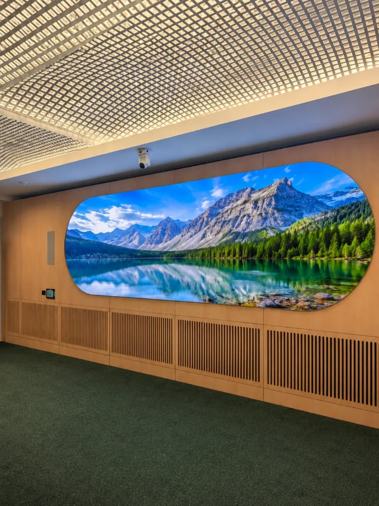 Oval LED screen showing a mountain lake, set into the wood wall beneath a backlit ceiling