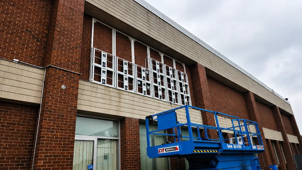 Structure porteuse d'un écran LED fixée sur la façade en brique d'un bâtiment, nacelle élévatrice au pied