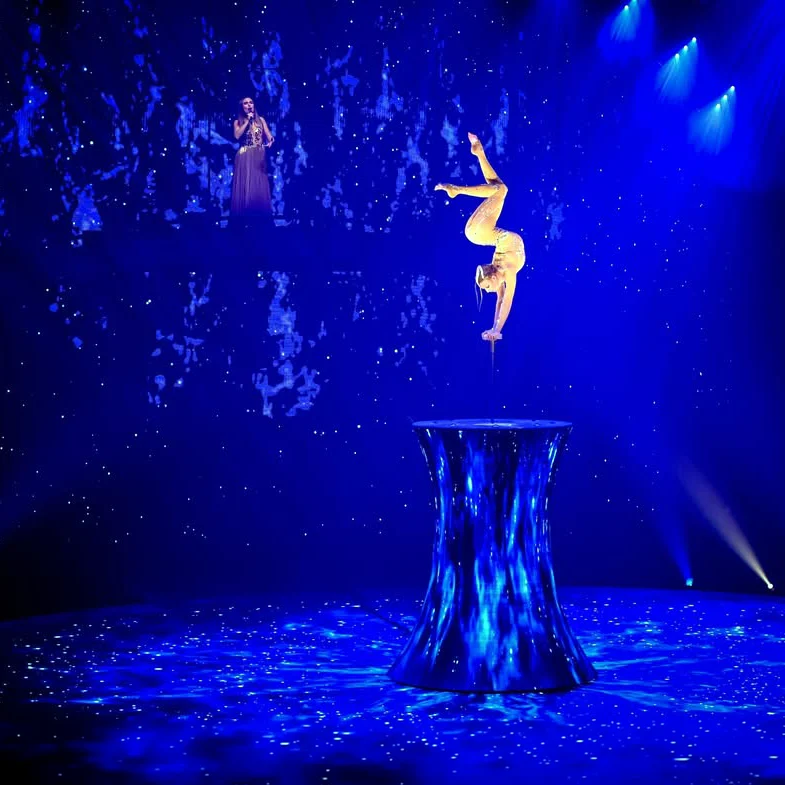 Acrobatic act on a blue-lit LED podium