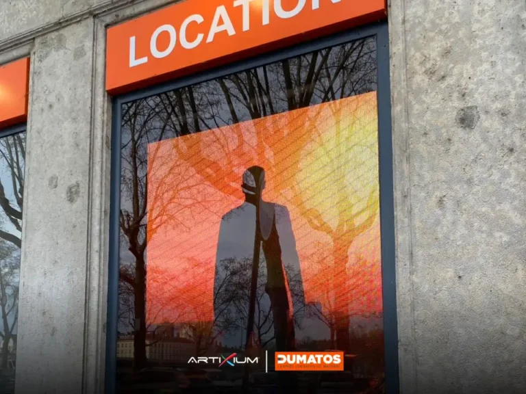 LED screen store – LED screen in the shop window showing an orange visual, quayside trees reflected on the glass
