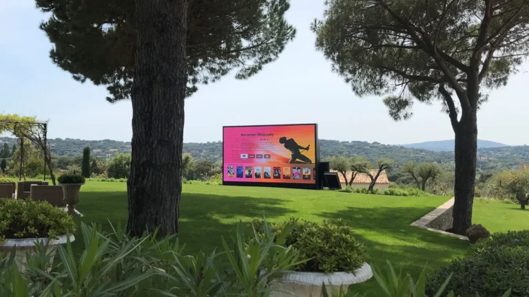 ECLIPSE LED screen showing a film menu on a villa lawn, wooded hills in the distance