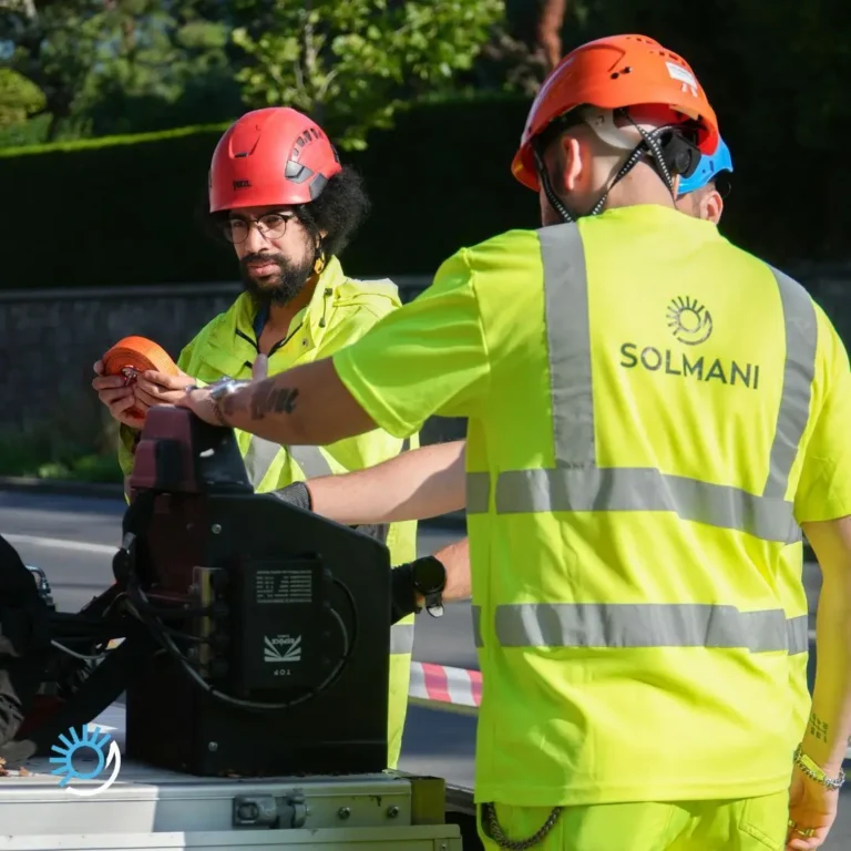 Deux techniciens en gilet haute visibilité manipulent une sangle lors d'une installation en bord de route