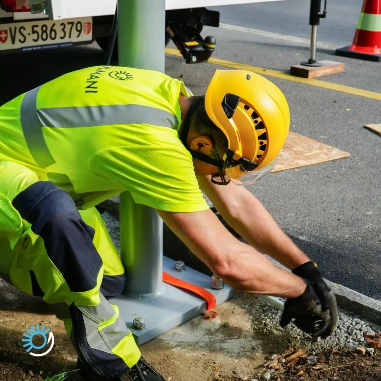 Technicien casqué fixant au sol la platine du mât support de l'écran d'information
