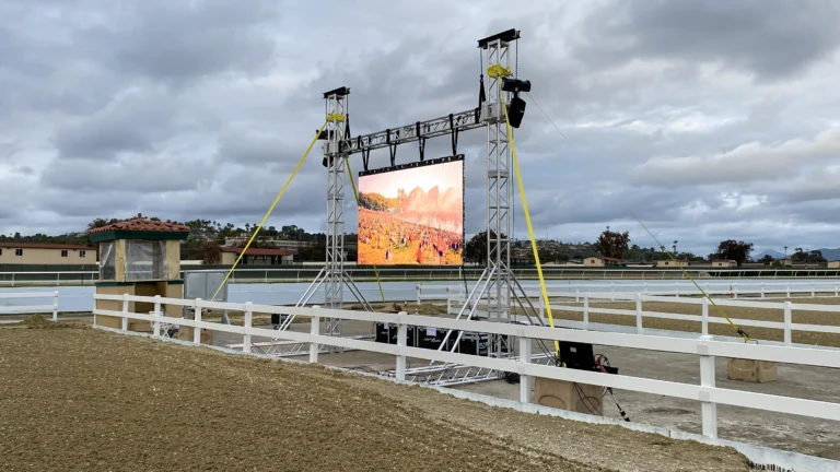 Outdoor LED display mounted on tower lifts beside an equestrian arena