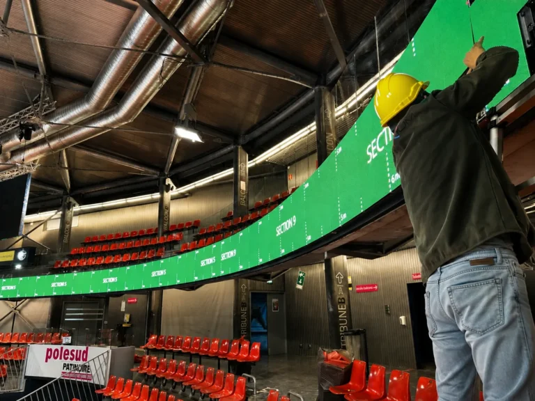 Technician aligning the cabinets of a curved perimeter LED system in an ice rink