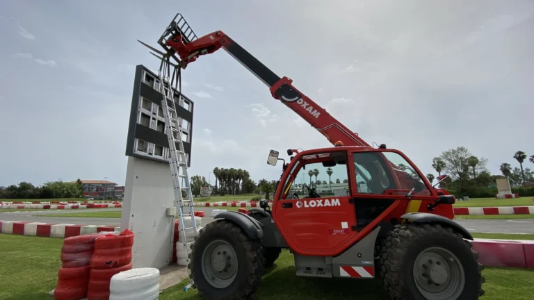 COBALT LED screen being lifted onto its concrete base by a telehandler beside the track