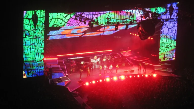 LED screen tour Johnny Hallyday – Concert stage seen from the stands, tall psychedelic LED video walls behind the backlit band