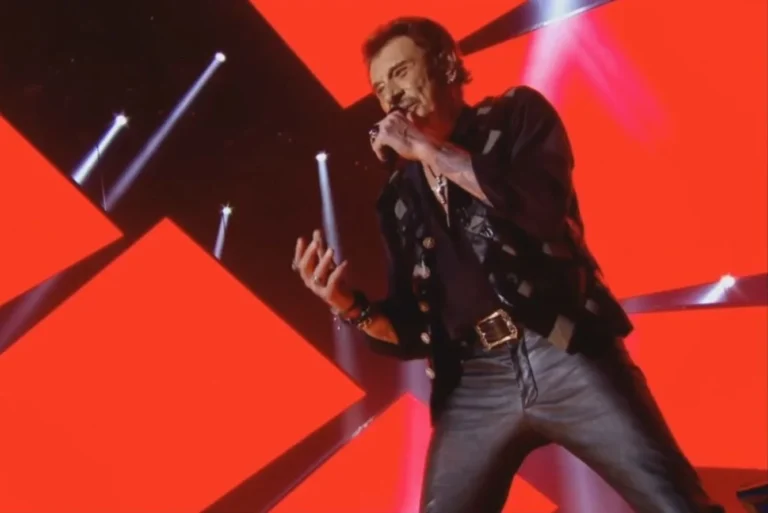 Close-up of the singer at the microphone against the bright red LED video wall on stage