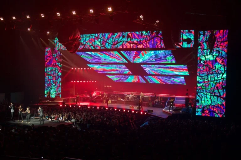 LED stage set with vertical side panels and angled overhead screens above the band