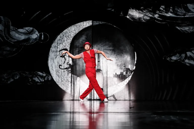 Artiste en rouge se détachant sur un décor LED noir et blanc figurant une lune stylisée sur scène