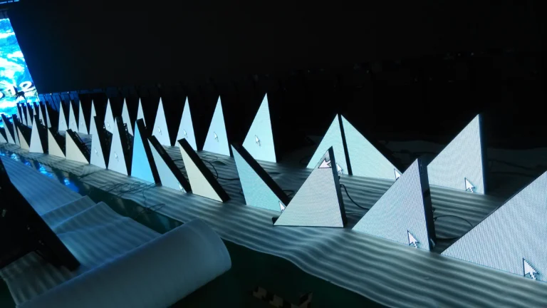 Triangular LED modules lined up and lit during the set build, cabling still exposed
