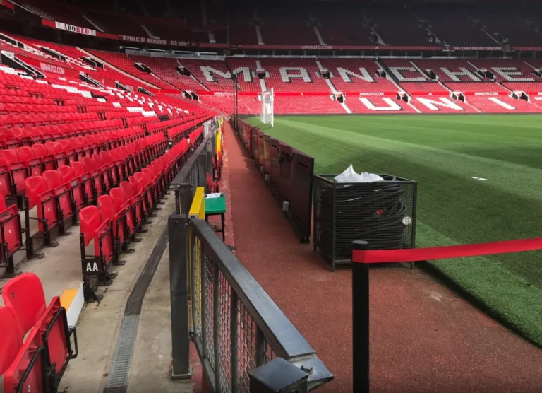 Pitchside at Old Trafford, perimeter LED system panels lined up along the track, empty stands