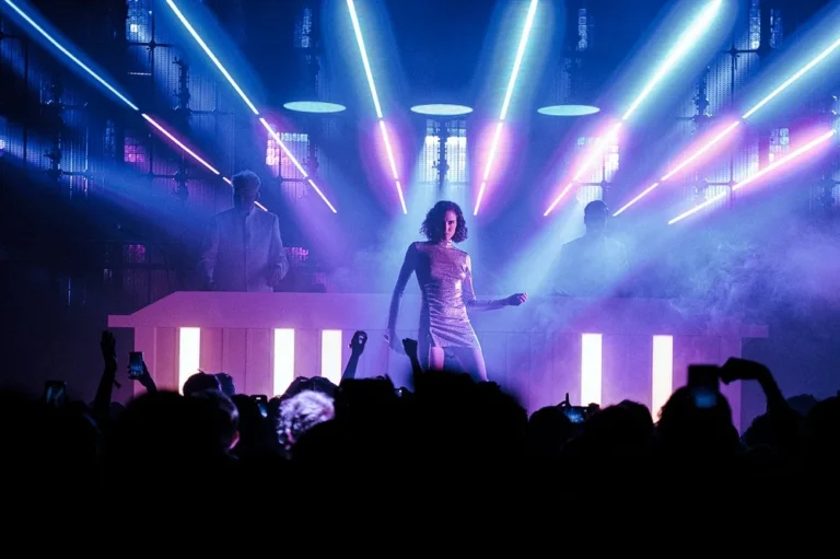Danseuse en robe à paillettes devant le pupitre DJ, faisceaux violets et mur LED en fond de scène