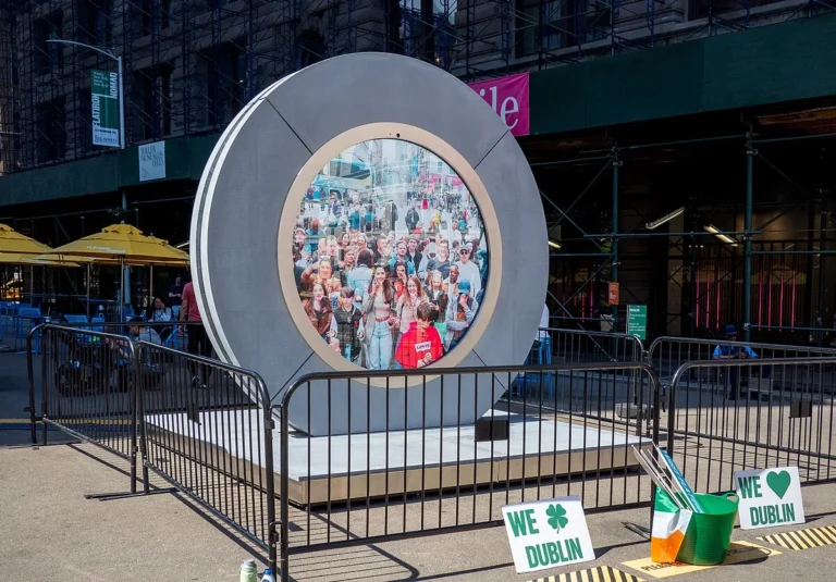 Man sitting arms outstretched at the foot of the LED portal showing New York placards