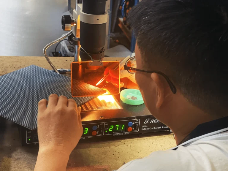 Technician replacing LEDs under a magnifying lamp at the hot-air rework station (LED screen repair)