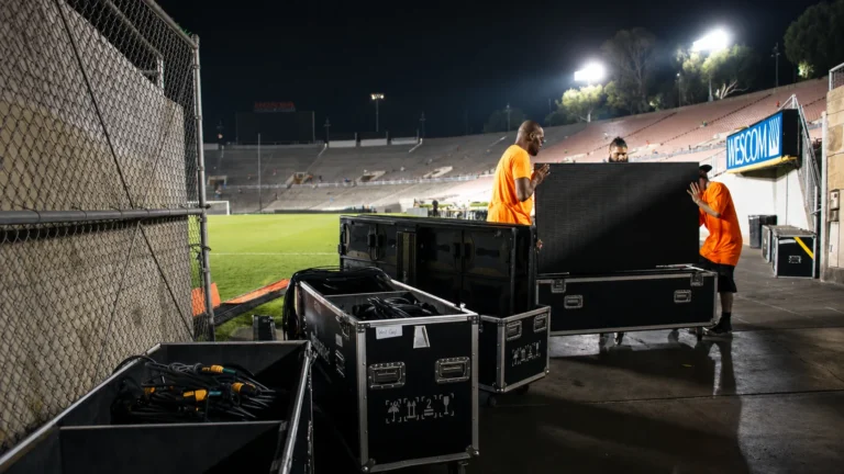 Perimeter LED cabinets being unpacked from their flight cases at night, pitch side