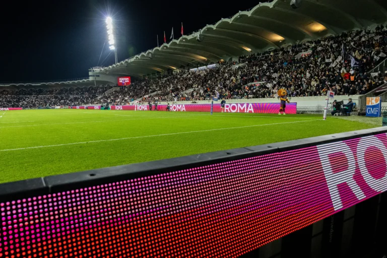 Écran LED stade rugby – Système LED périmétrique en gros plan diffusant une publicité, pelouse et tribunes combles