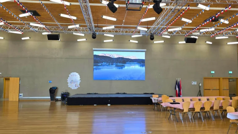 Salle polyvalente du lycée avec écran LED QWARTZ mural, estrade, guirlandes de fanions et tables