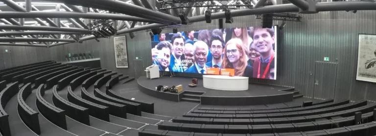 Mur d’images LED dans un auditorium en gradins, au-dessus d’une scène de conférence