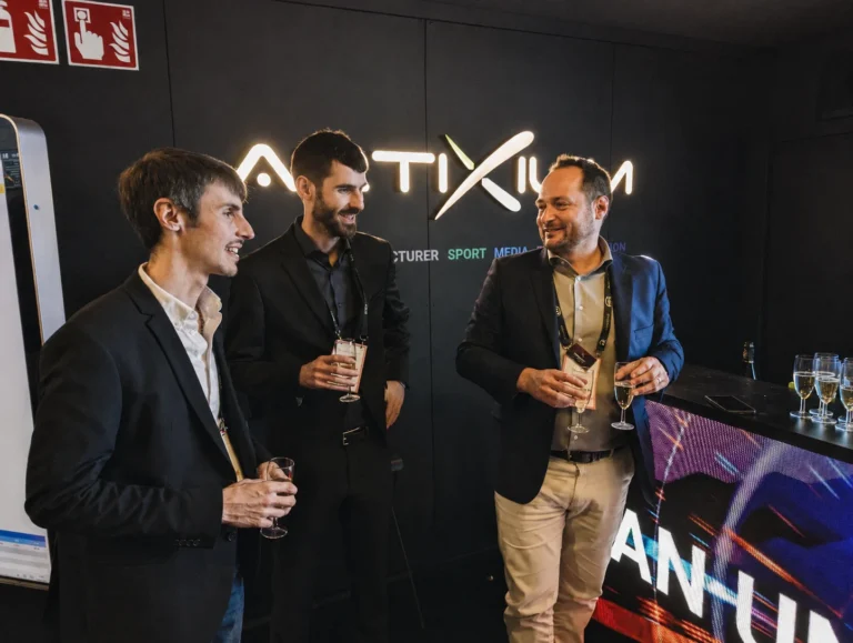 Trois collaborateurs Artixium, fabricant écran LED Lyon, en discussion devant le logo rétroéclairé de la marque