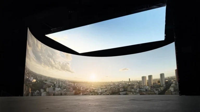 Curved LED display showing a city skyline at sunrise