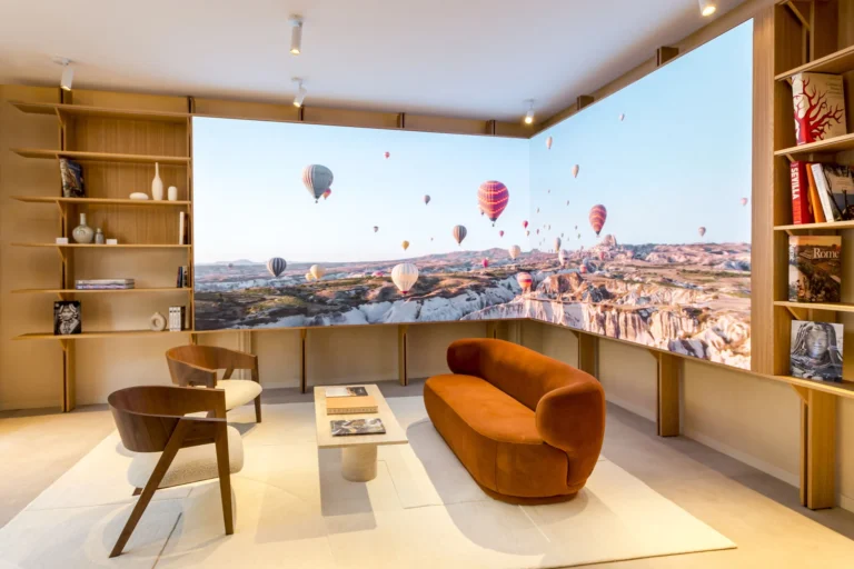 Salon de l’agence avec mur d’images LED d’angle diffusant des montgolfières au-dessus de la roche
