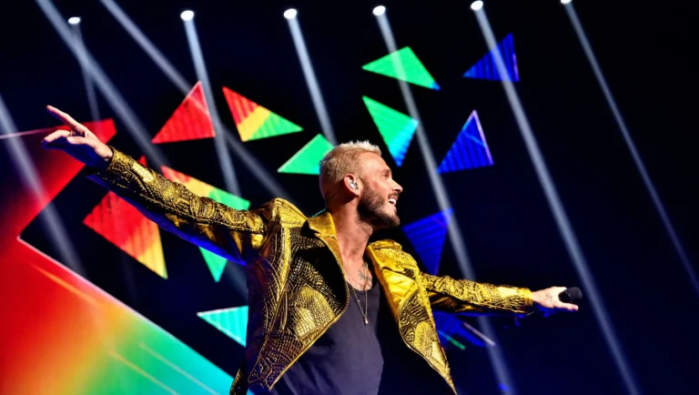 Performer on stage in front of a set of coloured triangular LED panels