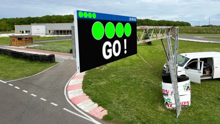 Écran LED extérieur en bord de piste de karting affichant les feux de départ verts et le signal GO