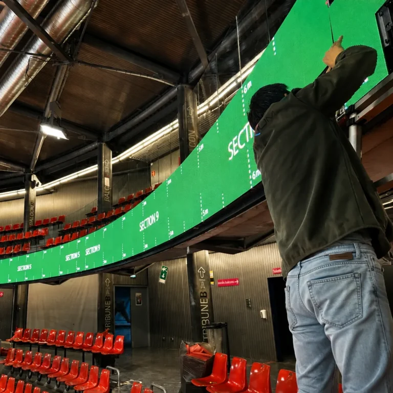 Bandeau LED périmétrique vert en bord de balcon dans une patinoire, technicien sur une échelle