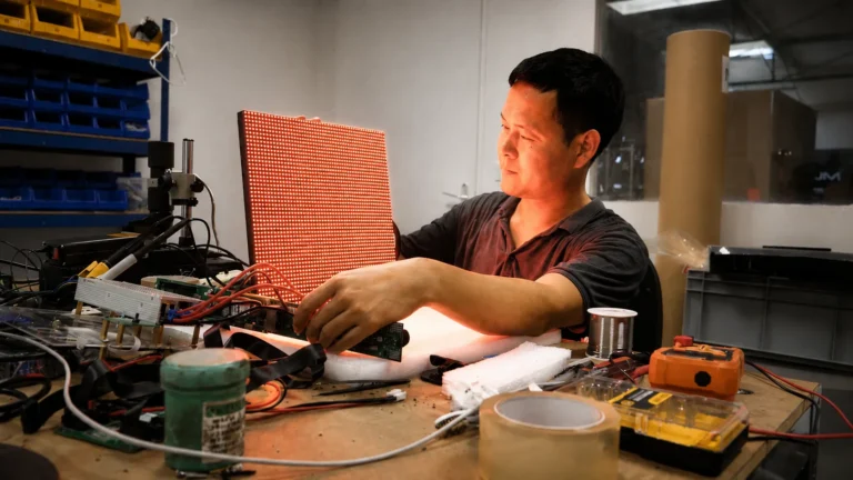 Technicien en atelier, module LED en main, outils de réparation sur l'établi