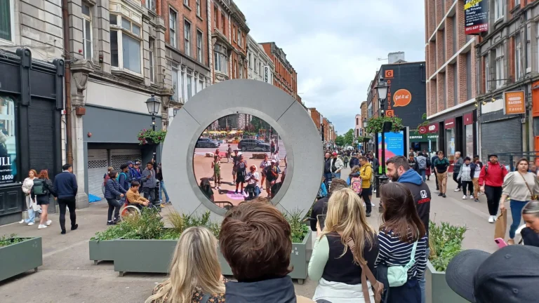 Onlookers watching the circular LED portal installed on a Dublin pedestrian street